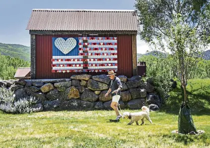  ?? Kelsey Brunner, The Aspen Times ?? A man and his dog pass by John Przonek's 3-D mural of an American fag displayed on the back of a bus stop at Lions Park behind Basalt Town Hall on Wednesday.