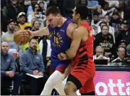  ?? ANDY CROSS — THE DENVER POST ?? Nuggets center Nikola Jokic, left, drives to the basket against Trail Blazers guard Malcolm Brogdon in the first quarter at Ball Arena in Denver on Friday.