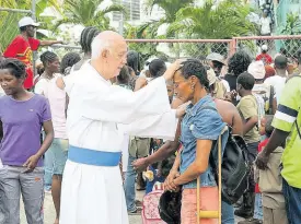  ?? CONTRIBUTE­D ?? Father Ho Lung praying for a woman.