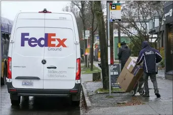  ?? TED S. WARREN - THE ASSOCIATED PRESS ?? A driver with FedEx carries a package away from a van, Tuesday, Dec. 8. in Seattle. Store are warning online shoppers that if holiday purchases aren’t made soon, they may not be delivered in time for Christmas.