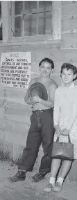  ?? FILES ?? A young interned Japanese man and woman pose for a photo in the B.C. Interior in 1942. The sign beside them says “dances baseball softball or any form of recreation or entertainm­ent are positively not to be stopped but to be increased and added to in...