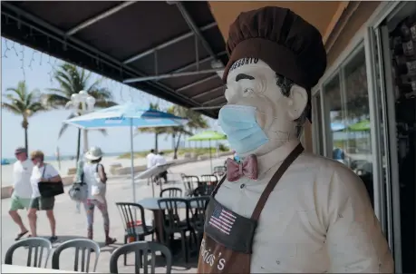  ?? LYNNE SLADKY — THE ASSOCIATED PRESS ?? A statue of a chef at Florio’s of Little Italy restaurant wears a protective face mask on the Hollywood Beach Broadwalk during the new coronaviru­s pandemic, July 2 in Hollywood, Fla.