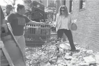  ?? JESSICA HILL/SPECIAL TO THE COURANT ?? New Britain mayor Erin Stewart, right, finds a brick in the rubble for Tina Santana, left, during demolition of Burritt Bank. Santana sang in her school choir as a child on the staircase inside the building and wanted to take a piece home of the building for nostalgia. Stewart and developer Avner Krohn held a brief ceremony to start demolition of Burritt, which Krohn will replace with a six-story apartment and retail building.