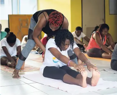  ??  ?? Yoga instructor Tanisha Hibbert assists Prestonite Bridget Francis into the seated Forward Fold.