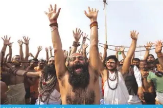  ??  ?? ALLAHABAD: Holy man Shiv Yogi Moni Swami cheers - surrounded by devotees after rolling towards the Sangam, the confluence of the rivers Ganges, Yamuna and mythical Saraswati, for a holy dip during the annual Magh Mela festival in Allahabad.— AFP