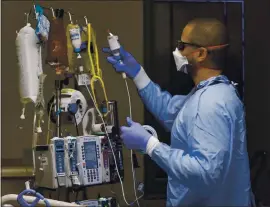  ??  ?? Nurse Louis Johnson treats a COVID-19 patient in the ICU at Regional.