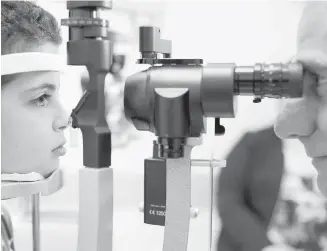  ?? AP ?? Dr. Albert Maguire checks the eyes of Misa Kaabali, 8, at the Children’s Hospital of Philadelph­ia. Misa was four years old when he received trial gene-therapy treatment for an inherited form of blindness. On Thursday, a U.S. Food and Drug...