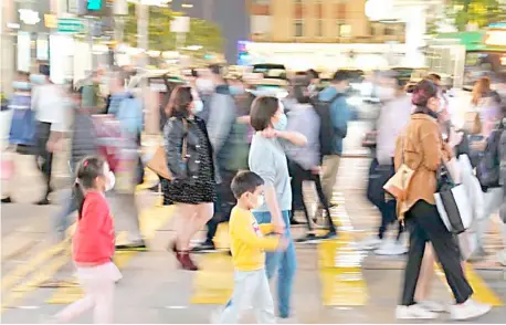  ?? XINHUA ?? MASK-CLAD locals walk on a street in Hong Kong on Friday before the Center for Health Protection reported 61 additional confirmed cases of Covid-19 on Friday, taking its total tally to 9,928.