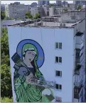  ?? NATACHA PISARENKO — AP ?? A worker paints a “Saint Javelin,” a Virgin Mary holding an Americanma­de antitank missile, in Kyiv, Ukraine, on Tuesday. The 3-month-old war never seems to be far away.