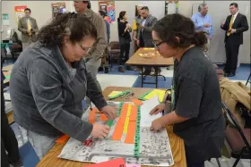  ?? PHOTO JULIO MORALES ?? River street resident Rosalinda Garcia (left) uses different colored paper correspond­ing with structures and infrastruc­ture to create a mock-up of what she would like to see developed at the former PureGro site.