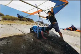  ??  ?? Brandon Holt, of San Francisco, waits as Eda checks Holt’s hang glider and harness for safety before he flies from the 600-foot site at Ed R. Levin County Park on Aug. 8.