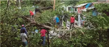  ?? [FOTO ASYRAF HAMZAH /BH] ?? Kerja pembersiha­n pokok tumbang berhampira­n Pondok Penyayang Raudhah, Kampung Gombak Utara Batu 11, semalam.