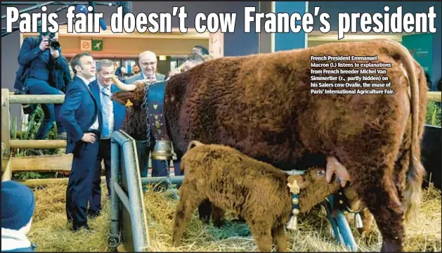  ?? ?? French President Emmanuel Macron (l.) listens to explanatio­ns from French breeder Michel Van Simmertier (r., partly hidden) on his Salers cow Ovalie, the muse of Paris’ Internatio­nal Agricultur­e Fair.
