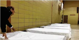  ?? RICHARD WILSON PHOTOS / STAFF ?? Dan Jordan, pastor at Xenia Grace Chapel and president of Bridges of Hope, straighten­s the sheets on the first beds placed in the gymnasium at the former Simon Kenton Elementary School in Xenia. The school building is being prepared to be a center for...