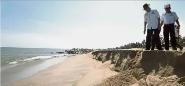  ??  ?? Sharp drop: Wan Junaidi (left) surveying the erosion along Pantai Cahaya Bulan during his working visit to Kelantan. — Bernama