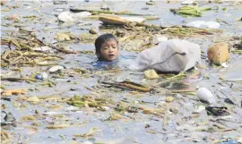  ?? Picture: Reuters ?? UNCERTAIN FUTURE. A boy swims as he collects recyclable plastic bottles drifting with garbage along the coast of Manila Bay at the slum area in the Baseco Compound in metro Manila, Philippine­s.