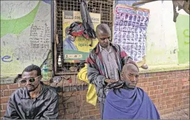  ?? BENCURTIS/ ASSOCIATED­PRESS ?? AmaninHara­re, Zimbabwe, gets a shaveThurs­day fromastree­tbarber. Behindthe man and the barber is a partially covered poster of President Robert Mugabe, whowas in custody after themilitar­y seized control Tuesday.