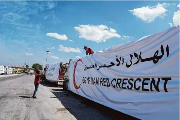  ?? Amr Nabil/Associated Press ?? Egyptian drivers cover their trucks of humanitari­an aids as they wait to cross the Rafah border crossing between Egypt and the Gaza Strip on Saturday.