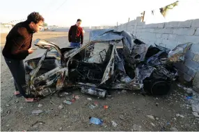  ?? (Reuters) ?? MEN LOOK at the wreckage of a burnt car after a suicide bomber detonated a pick-up truck this week in Sadr City, a heavily populated poor Shi’ite suburb of Baghdad.