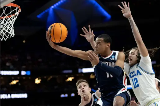  ?? ?? Gonzaga guard Nolan Hickman scoops under UCLA forward Mac Etienne for a shot that failed to drop in first-half action in the nightcap at T-mobile Arena. Gonzaga advanced to the Elite Eight with a 79-76 victory.