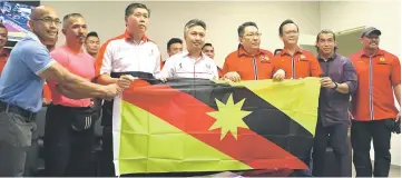  ??  ?? Snowdan (fifth right) presents the state flag to Sarawak team manager Andy Ismail (third right) while (from left) Malvern, Buda, Ong, Wee, Azizul and Sarawak head coach George Awi William look on.