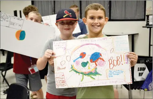  ?? (NWA Democrat-Gazette/Annette Beard) ?? Cash Meyers (from left), 9; Mason Blood, 9; and Bentley Keene, 9, show off their posters that describe their imaginary planets during Space Camp at Pea Ridge Middle School.