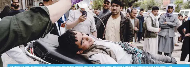  ?? —AFP ?? KABUL: Medical staff move a wounded youth on a stretcher outside a hospital in Kabul on April 19, 2022, after two bomb blasts rocked a boys’ school in a Shiite Hazara neighbourh­ood killing at least 6 people.