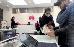  ?? AP/NG HAN GUAN ?? Tourists examine a laptop computer Thursday at a Huawei store in Beijing. Meng Wanzhou, Huawei Technologi­es’ chief financial officer, was arrested in Canada last weekend on fraud charges and faces extraditio­n to the U.S.