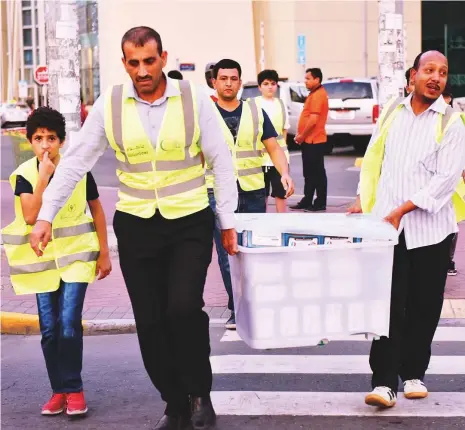  ??  ?? Volunteers carry iftar kits to motorists at one of the traffic signals near Al Wahda Mall in Abu Dhabi.