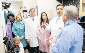  ?? OCTAVIO JONES/TAMPA BAY TIMES ?? Gov. Ron DeSantis, right, and other officials watch while Andrew Cannons, far right, laboratory director, explains the testing procedures of potential coronaviru­s cases on Monday at the Florida Department of Health Laboratory in Tampa.