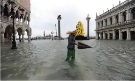  ??  ?? A woman wades through floods in Venice; residents estimated the water level to be as high as 1.5 metres. Photograph: Andrea Merola/EPA