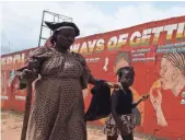  ??  ?? A child with her blind mother walks past a mural carrying messages on the deadly Ebola virus on a street corner in Monrovia, Liberia.
AHMED JALLANZO, EUROPEAN PRESSPHOTO AGENCY