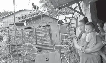  ??  ?? Residents watch as family members (left) secure the roof of their house before Mangkhut makes landfall in the city of Tuguegarao, Cagayan province.