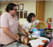  ?? ?? Asistentes técnicos de la biblioteca pública de Woodland Frank Briceño Jr. y Alexa Arredondo-Aguilar preparan nachos para el evento.