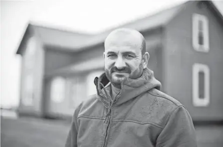  ?? COURTNEY HERGESHEIM­ER/ COLUMBUS DISPATCH ?? Amjad Ashnawi, an Iraqi refugee, stands Wednesday outside a Marysville farm he owns with his wife and children.