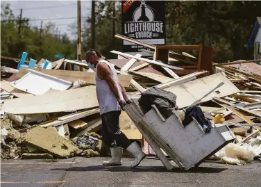  ?? David Grunfeld / Associated Press ?? A man drags baptismal stairs to the debris pile while helping gut the Lighthouse Church in Lafitte, La.