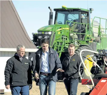  ?? MARK TAYLOR/THE CANADIAN PRESS ?? Prime Minister Justin Trudeau chats with farmers Rod Lewis, left, and Lewis’s son near Gray, Sask., Thursday. Speaking in Saskatchew­an, Trudeau addressed leaked informatio­n that indicated U.S. President Donald Trump was considerin­g terminatin­g the...