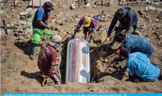  ??  ?? LIMA: Relatives bury the coffin of a suspected COVID-19 victim at the Nueva Esperanza cemetery, one of the largest in Latin America, in the southern outskirts of Lima. — AFP