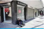  ??  ?? TRIPOLI: A Lebanese man sits next to a closed store in the northern city of Tripoli. —AFP