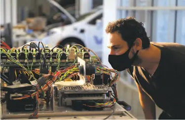  ?? Jim Wilson / New York Times ?? Alan Mond, an engineer at the selfdrivin­g car company Voyage, checks components of the “hardware in the loop” system in Palo Alto. The company has arranged for engineers to be able to run tests remotely.