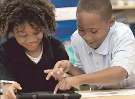  ?? Bob Chamberlin ?? KING SHELTON and Zylan Giles, students at Broadacres Avenue Elementary in Carson, explore an iPad provided by the L.A. school district’s $1-billion project.