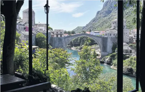  ?? AFP ?? The deserted ‘Old Bridge’ of Mostar, usually riddled with groups of tourists, is seen from an empty restaurant terrace on May 8.