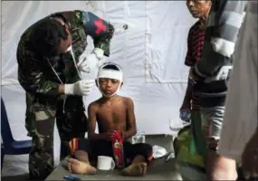  ?? FAUZY CHANIAGO—THE ASSOCIATED PRESS ?? A military paramedic tends to a boy who suffers from a head injury from Sunday’s earthquake at a makeshift hospital in Kayangan, Lombok Island, Indonesia, Wednesday. The north of Lombok has been devastated by the magnitude 7.0 quake that struck Sunday...