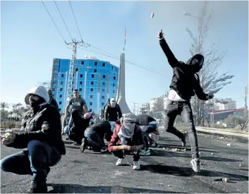  ?? ABBAS MOMANI/GETTY IMAGES ?? Palestinia­n protesters clash with Israeli troops near an Israeli checkpoint in the West Bank city of Ramallah on Friday. Israel deployed hundreds of additional police officers following Palestinia­n calls for protests of U.S. President Donald Trump’s...