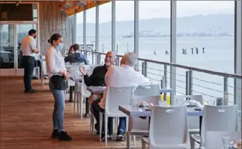  ?? Ben Margot/Associated Press ?? Customers at Mission Rock Resort Restaurant in San Francisco interact with their waitress on Friday, which was the first day outdoor dining was allowed in the city’s restaurant­s since the shutdowns caused by the COVID-19 pandemic.