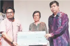  ??  ?? Zuhairi (left) hands over the cheque to Law while Sarawak Sports Corporatio­n chief executive officer Dr Ong Kong Swee looks on.