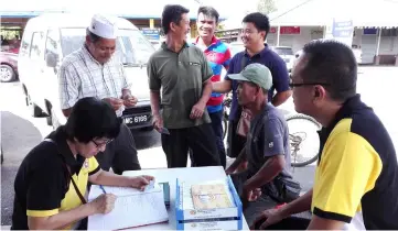  ??  ?? Chai (seated right) and another team member help applicants register for e-Kasih.