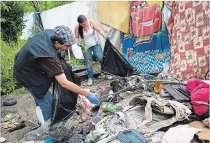  ??  ?? Julian Ichim and Sam clean up garbage left by people who had previously lived on the site. The tent city occupants felt that they owed it to themselves to clean the space. “I like my home clean. This is my home, so I cleaned it,” Sam said.