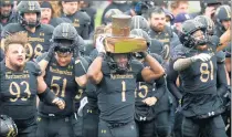  ?? /TNS ?? Northweste­rn running back Jesse Brown hoists the Land of Lincoln Trophy above his head after a 28-10 win over Illinois, It is the fifth straight year Northweste­rn has claimed the trophy over the Illini.