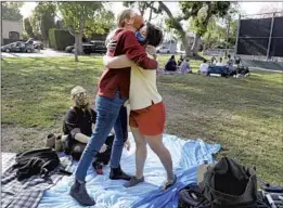  ?? Gary Coronado Los Angeles Times ?? JESSICA HOLZER hugs Madeline Brozen at Plummer Park for the first time since the pandemic began. Holzer’s fiance, Brandon Carpenter, is seated.